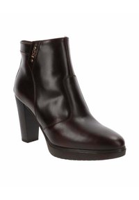 Bottine en cuir marron foncé avec un talon à bloc et une languette latérale ornée de deux rivets métalliques sur fond blanc.