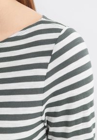 Gestreepte top met groene en witte horizontale strepen, ronde halslijn en textuur gebreide stof, met details van schouder en mouw.