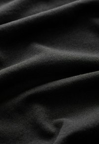 Tela de algodón negra con una textura suave, que presenta sutiles estiramientos y pliegues, creando una apariencia ligera y suave.