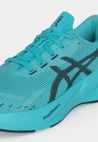 Φωτεινό τουρκουάζ αθλητικό παπούτσι Asics με μαύρο λογότυπο, κορδονάκια και ορατή την επένδυση Amplifoam στο πλευρό της σόλας.