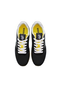 Černé sportovní boty s síťovanými detaily, bílé tkaničky a žlutý interiér. Na jazyku je znak a podrážka je z texturované gumy.