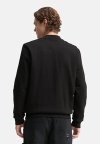 Schwarzer Pullover mit rundem Ausschnitt, gerippten Bündchen und Saum. Glatter, strukturierter Stoff. Rückansicht zeigt ein klares Design mit minimalen Details.