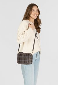 Borsa a tracolla in tessuto a scacchiera in marrone, blu e crema, di forma rettangolare, con chiusura a zip e tracolla regolabile.
