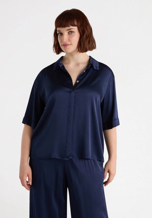 Camicetta in satin blu navy con maniche corte, colletto e chiusura con bottoni. Tessuto liscio con una vestibilità comoda.