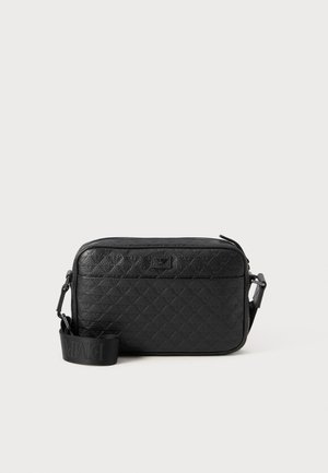 Black textured crossbody bag with embossed geometric pattern and adjustable strap featuring brand logo.
