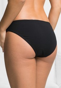 Bas de bikini noir taille haute en tissu extensible, avec une texture lisse et un design simple sans ornements.