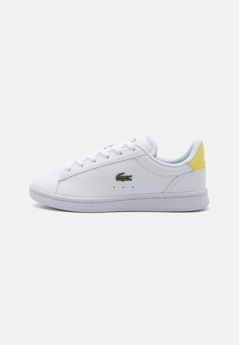 Hvite lær sneakers med en strømlinjeformet design, snøring, grønne og gule detaljer, og en liten brodert krokodillelogo på siden.