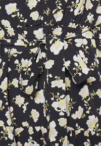 Robe en tissu noir avec un motif floral blanc et jaune. Comprend une ceinture nouée à la taille et un design plissé. Texture douce.