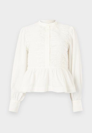 Λευκό μπλουζάκι μακρυμάνικο με πτυχωτές μπροστινές πιέτες, λαιμόκοψη με ζώνη, κούμπωμα με κουμπιά και στρογγυλεμένη ζώνη με βολάν.