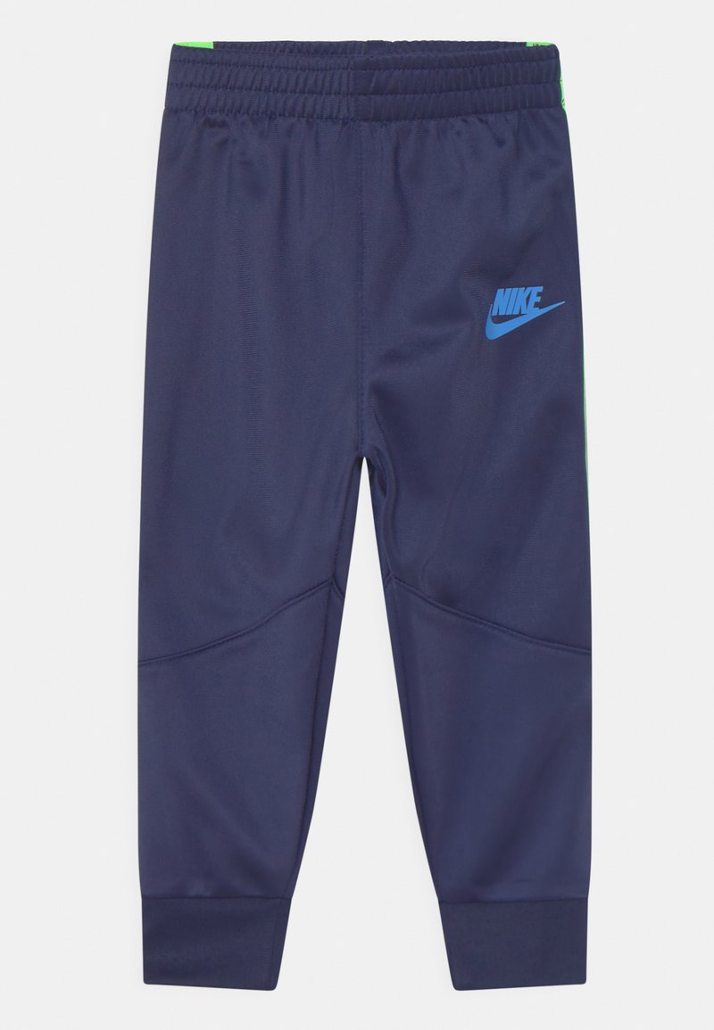 Pantalones de chándal de Nike en azul marino, de tamaño infantil, con cintura elástica, tobillos ajustados y logo de Nike en azul claro en el muslo izquierdo.