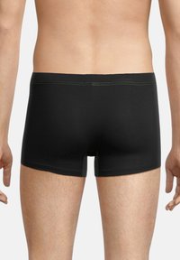 Black boxer briefs with a smooth texture, featuring green stitching along the waistband and leg openings. The design is fitted and elastic.