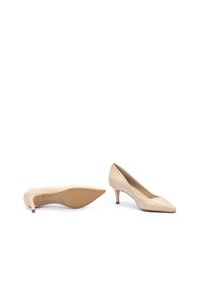 Zapatos de tacón alto de charol color nude con punta afilada y tacón delgado. Textura suave con un brillo sutil. Suela de color claro.