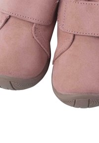 Scarpe in suede rosa con punta arrotondata e dettagli con cinturino in velcro. Le suole sono in gomma con un motivo testurizzato per una migliore aderenza.