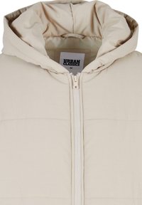 Beige välklädd pufferjacka med huva, som har en dragkedja framtill, kviltad textur och en etikett med texten "URBAN CLASSICS" inuti kragen.