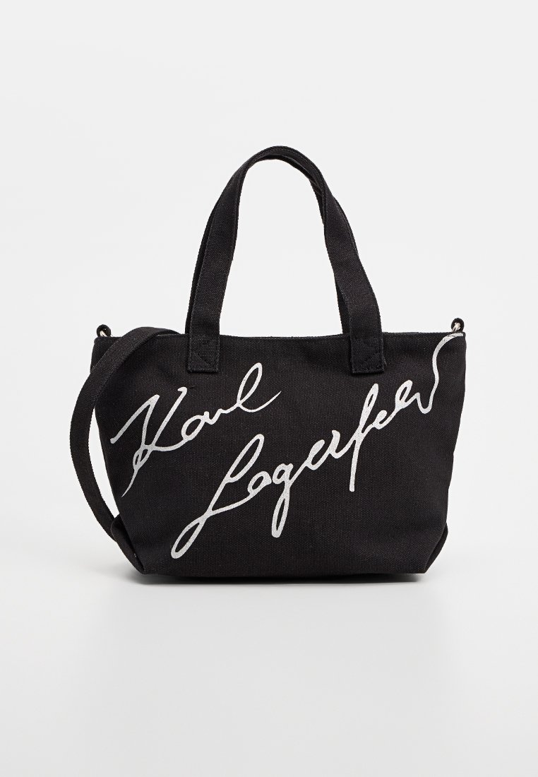 Sac fourre-tout rectangulaire noir avec doubles poignées et signature blanche "Karl Lagerfeld" sur le devant, incluant une bandoulière réglable.