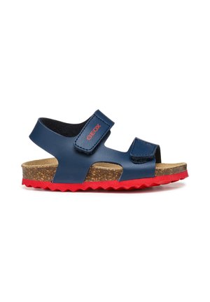 Sandalo per bambini blu navy con cinturini in velcro rossi con marchio, sottopiede in sughero e suola in gomma rossa testurizzata.