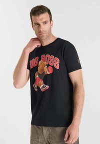 Camiseta de algodón negra con un estampado gráfico de un oso en ropa de boxeo y el texto "BIG BOSS". Cuello redondo y mangas cortas.