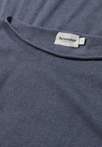 Smaragdgrüner Strickpullover mit rundem Halsausschnitt. Etiketten angezeigt: "hessnatur" und Größe "S." Die Textur ist glatt mit einem feinen Maschenbild.