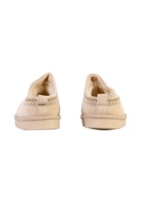 Paire de chaussons beige en daim à enfiler avec doublure en peluche, détail de couture blanche le long du col du talon, vus de dos sur un fond blanc.