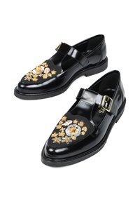 Czarne lakierowane buty na płaskiej podeszwie z paskiem T, ozdobione misternym haftem w złotym i białym kolorze. Okrągły czubek.