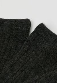 Schwarze gestrickte Socken mit geripptem Textur, die einen verstärkten Bündchen und eine weiche, fuzzy Oberfläche aufweisen. Eine Nahaufnahme zeigt die Details des Stoffes.