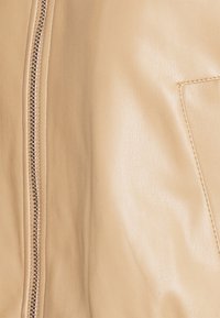 Beige läderjacka med en central dragkedja, slät yta och en sidoficka med sömdetaljer.