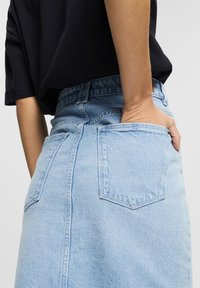 Vaalea sininen farkkuhame, jossa on korkea vyötärö, kaksi takataskua ja pehmeä rakenne. Suunnittelu on yksinkertainen ja suora.