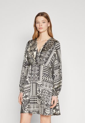 Svart og hvit mønsterkjole med dyp V-hals, lange ermer og en avslappet passform. Stoffet har intrikate geometriske og blomsterdesign.
