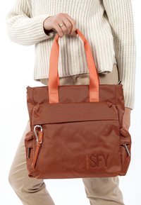 Brūna teksturēta soma ar oranžām rokturiem. Izstrādājumā ir rāvējslēdzēja kabata un sānu metāla akcenti. Izstrādāta gan funkcionalitātei, gan stilam.