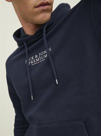 Hanorac bleumarin cu buzunar kangaroo, glugă cu șnur și logo imprimat "JACK & JON'S PREMIUM" în text alb contrastant.