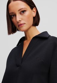 Dark navy sweatshirt with a collared neckline and a subtle embroidered logo on the chest. Smooth fabric texture, relaxed fit design.