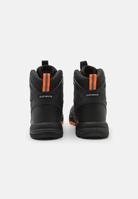 Mustat nilkkakengät, joissa on teksturoitu materiaali, oranssit yksityiskohdat ja pystysuora hihna takana. Vankka pohja pidon takia.