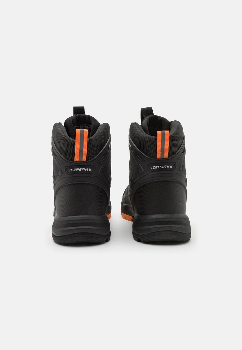 Zapatos negros de tobillo con material texturizado, con acentos naranjas y una correa vertical en la parte posterior. Suela resistente para tracción.