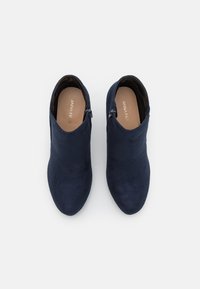Stivali alla caviglia blu navy con una morbida texture in camoscio, caratterizzati da una punta affusolata e zip laterali per una facile indossabilità. Il nome del marchio è visibile all'interno.
