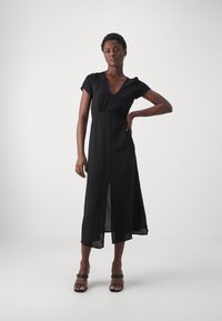 Black, mid-length dress with a V-neck, short sleeves, and a front slit. Made of smooth fabric, it falls elegantly around the body.