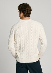 Maglione a treccia color crema, con un motivo testurizzato, polsini e orlo a costine, collo a giro e maniche raglan.