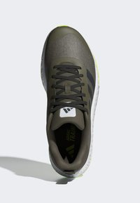 Grüner Sport Schuh mit einer strukturierten, atmungsaktiven Oberseite, schwarzen Akzenten und einer weißen Mittelsohle, die eine leuchtend grüne Außensohle aufweist.