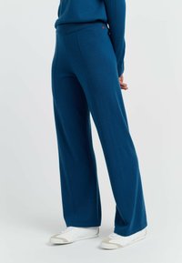 Weite, gestrickte Hosen in tiefblau mit strukturiertem Finish. Mit hohem Bund und subtilen roten Akzenten in der Hüftgegend.