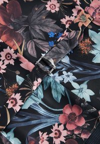 Stoff mit einem floralen Muster in verschiedenen Farben, darunter Pink, Rot und Blau, auf einem schwarzen Hintergrund; enthält eine silberne Metallspange.
