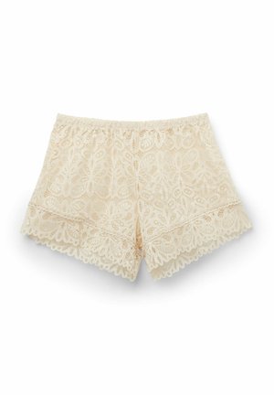 Spetsshorts i ljust beige med elastisk midja, med blommönster och vågiga kanter längs fållen för extra detalj.