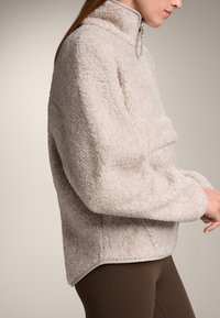 Fleece pullover in lichtbeige, met een hoge kraag, ritssluiting en een gestructureerd, zacht oppervlak. Geaccentueerd met contrasterende afwerking aan de zoom.