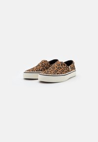 Slip-on skor med ett brunt leopardmönstrat tygöverdrag, svarta detaljer och en vit gummisula. Slät textur med elastiska sidopaneler.