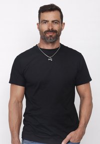 Svart bomullströja med klassisk rund hals och korta ärmar, som har en mjuk textur. Kombinerad med ett silverfärgat kedjehalsband med en berlock.