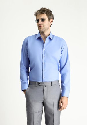 Hellblaues Hemd mit langen Ärmeln, glatter Oberfläche und transparenten Knöpfen, kombiniert mit hellgrauen Hosen.
