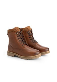 Une paire de bottines en cuir marron à lacets avec un col rembourré et des semelles en caoutchouc beige sur fond blanc.