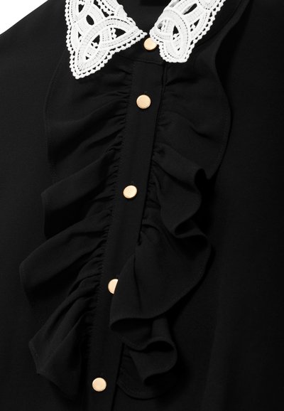 Bluză neagră cu guler din dantelă albă, având un front plisat și nasturi aurii pe centru. Textură de țesătură fină.