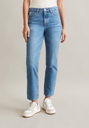 Light blue denim jeans with a high waist, straight leg cut, and five-pocket design, worn with white and beige sneakers.