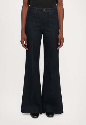 Dark blue high-waist wide-leg jeans with front seams worn by a person standing against a plain white background.
