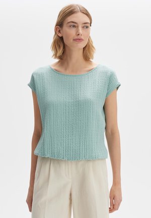 Light teal textured short-sleeve top with a round neckline, featuring a relaxed fit and subtle ribbed pattern. Pairing with cream-colored pants.