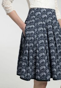 Rok met bloemenpatroon, gemaakt van donkere stof met plooien, voorzien van zakken en een contrasterende afwerking aan de zoom.